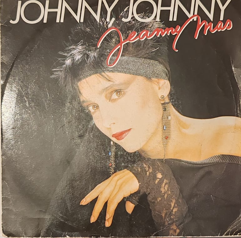 Jeanne Mas sur scène en concert années 80, interprétant sa chanson 'Sensuelle' avec une robe noire élégante et une ambiance lumineuse typique des années 1980.